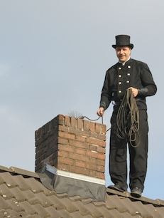Bild von Frank Rinne in Schornsteinfegermontur auf dem Dach 